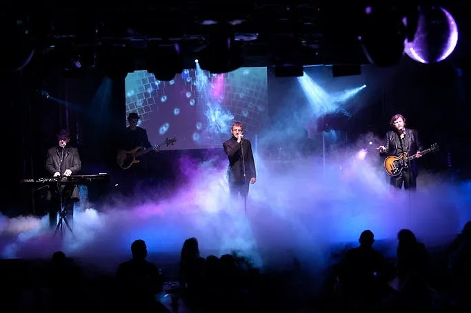 The Australian Bee Gees Show full live band performing on stage in purple disco haze and lights