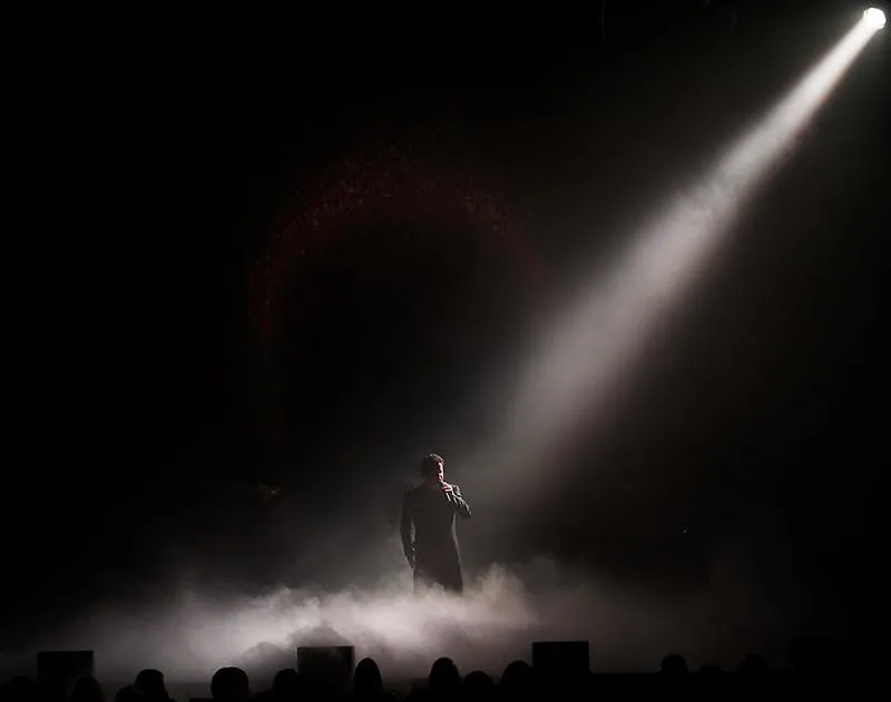 Donny Osmond silhouetted on stage in a single dramatic spotlight beam through haze