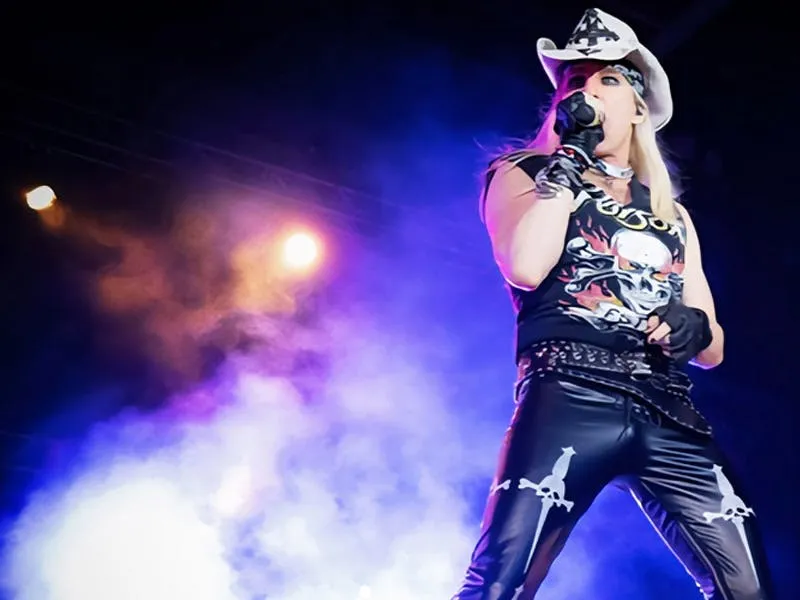 Ikons of Rock lead singer in a cowboy hat and skull tank performing under stage lights at The STRAT Theater Las Vegas