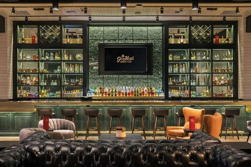 The bar and lounge area at Jimmy Kimmel's Comedy Club with shelves of liquor and plush seating