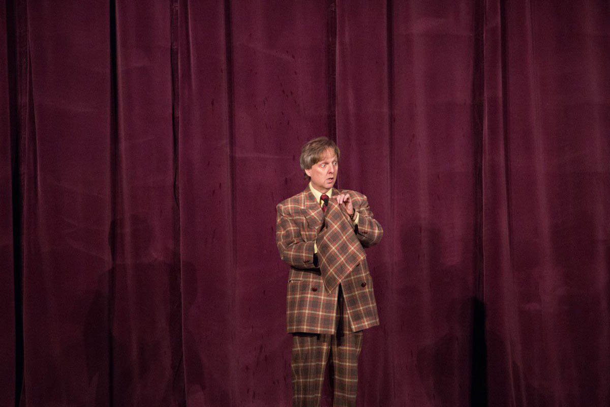 Mac King in his signature plaid suit standing on stage at Thunderland Theater, Excalibur Hotel and Casino Las Vegas