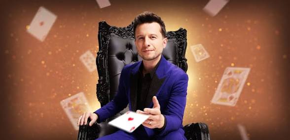 Mat Franco seated on an ornate golden throne in a purple suit with playing cards swirling through the air around him — promotional image for Magic Reinvented Nightly at The LINQ Hotel Las Vegas