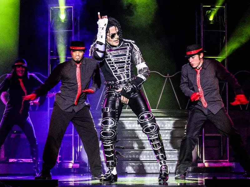 MJ Live lead performer mid-pose with two fedora-wearing dancers at Saxe Theater, Planet Hollywood Las Vegas