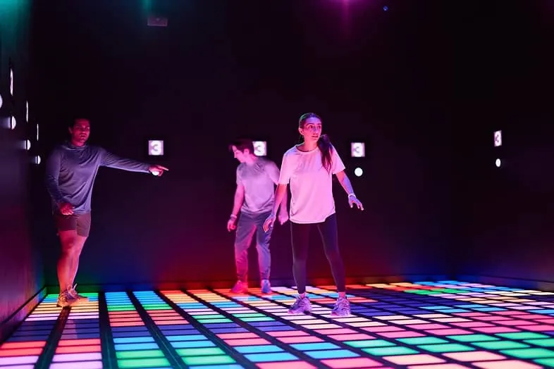 Guests competing on a lit-up interactive game floor inside Activate