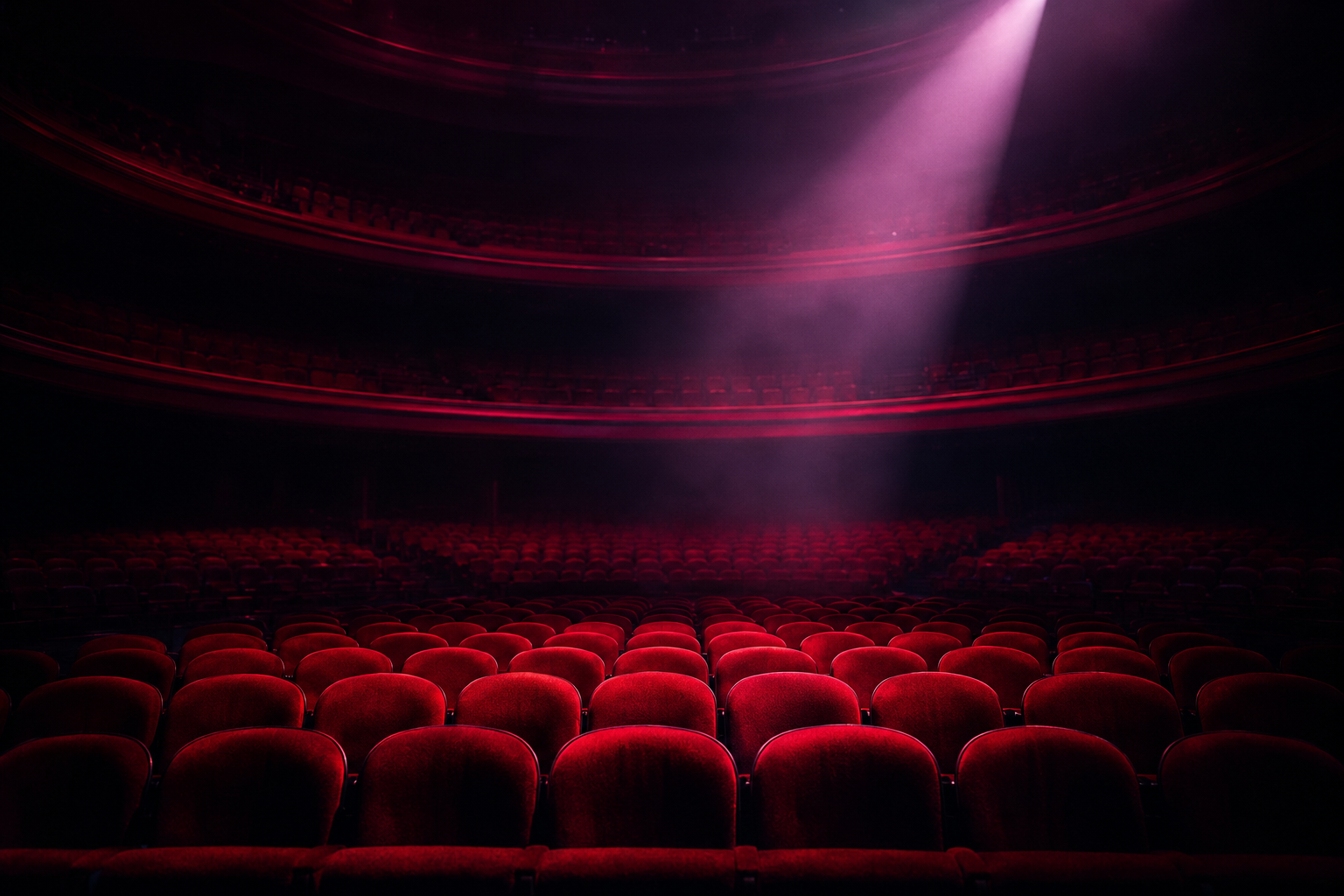 Empty Las Vegas theater interior with rows of plush red velvet seats illuminated by a single dramatic spotlight from above, suggesting a world-class performance venue