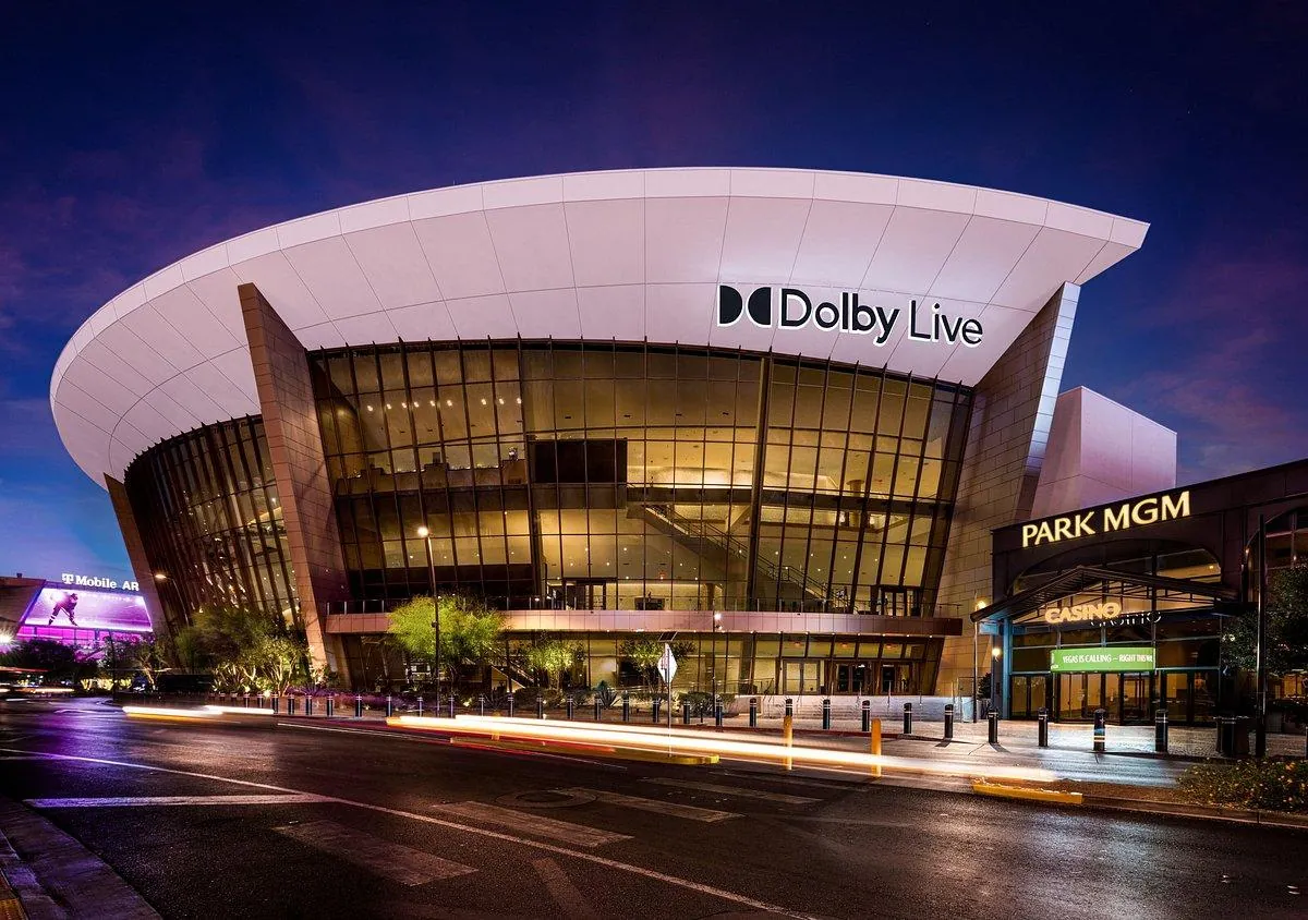 Dolby Live at Park MGM exterior at night — the modern curved white facade lit up on the Las Vegas Strip