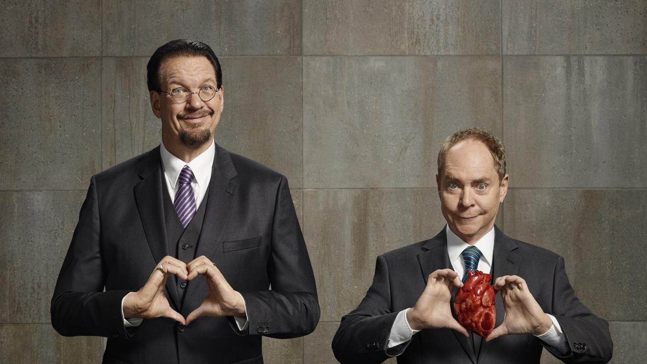 Penn Jillette making a heart shape with his hands while Teller holds a realistic prop heart — Penn & Teller Las Vegas show promotional photo at the Rio Hotel