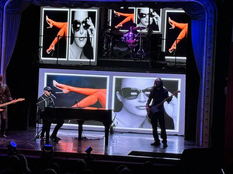 Piano Man band and dancers performing on stage with large video screens at the V3 Theater