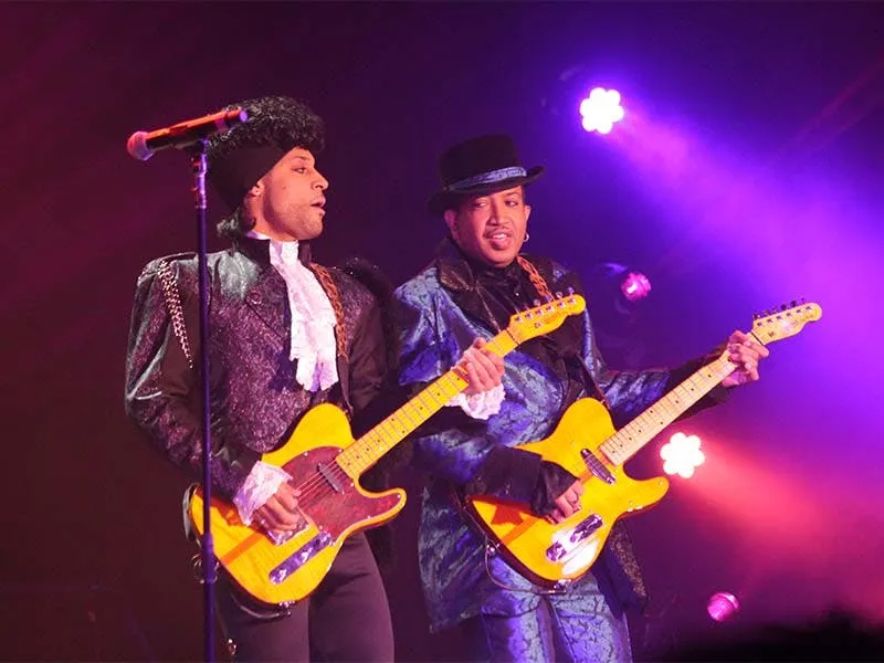 Purple Reign live band performing on stage with guitars under purple stage lighting