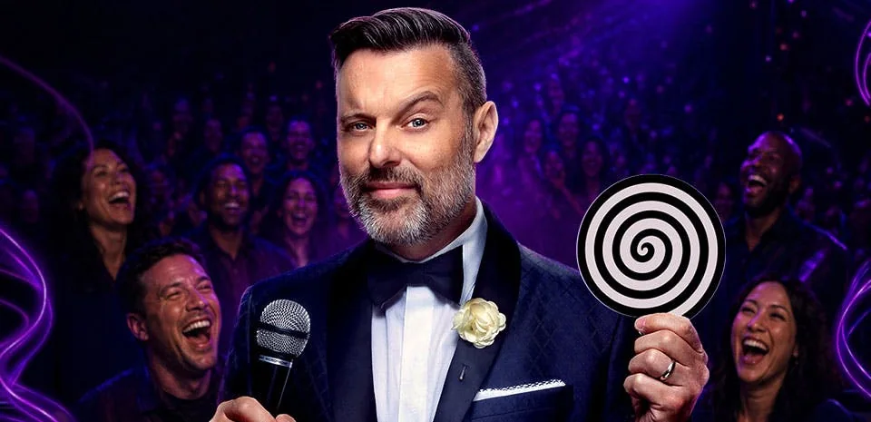 Steve Falcon in a tuxedo holding a microphone and a hypnosis spiral, laughing audience behind him — Comedy Hypnosis Hour at MGM Grand Las Vegas