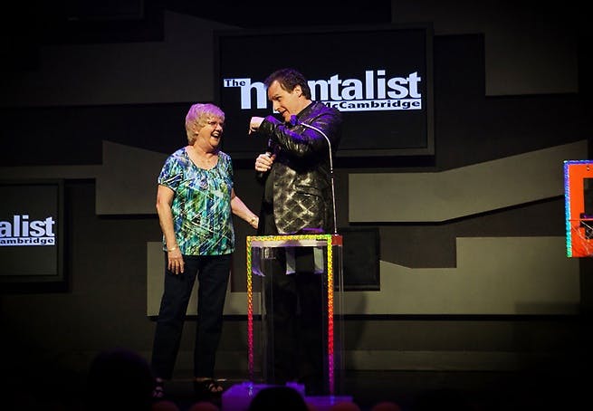 Gerry McCambridge performing on stage at the V Theater with a female audience volunteer standing beside him during The Mentalist Las Vegas at Planet Hollywood