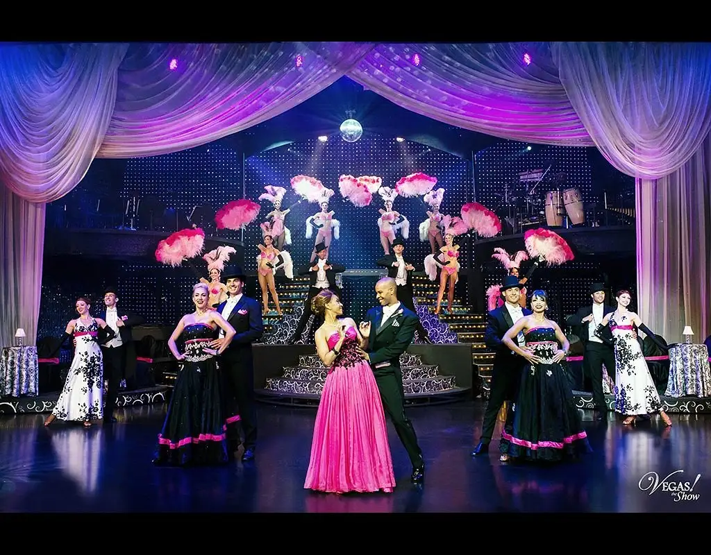 VEGAS! The Show performers in pink and black ballgowns with feather fans on stage at Saxe Theater